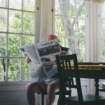 old man sitting in kitchen reading newspaper