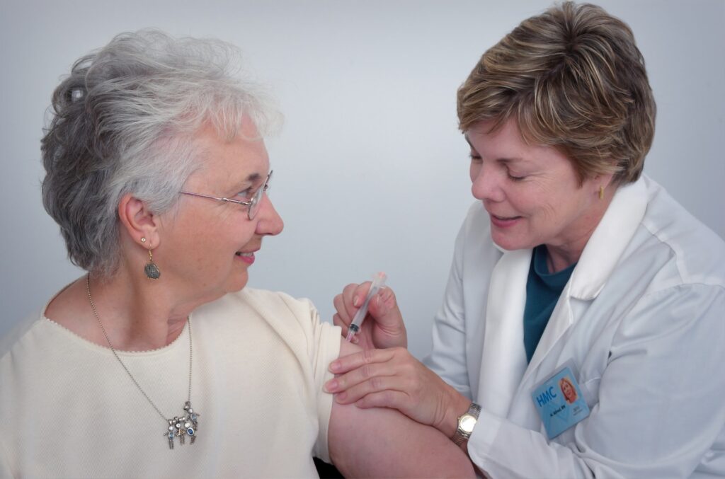 female doctor giving senior woman an immunization