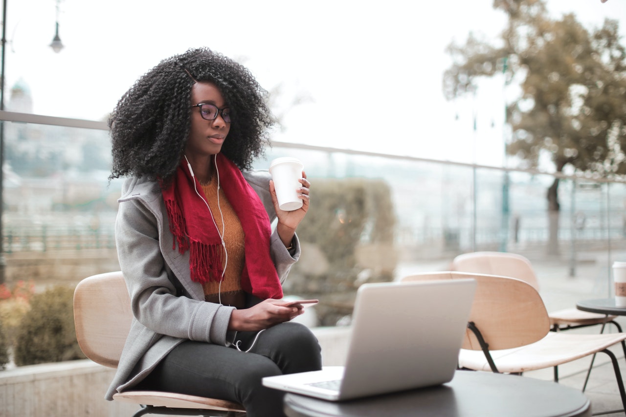 woman with coffee working on laptop outside