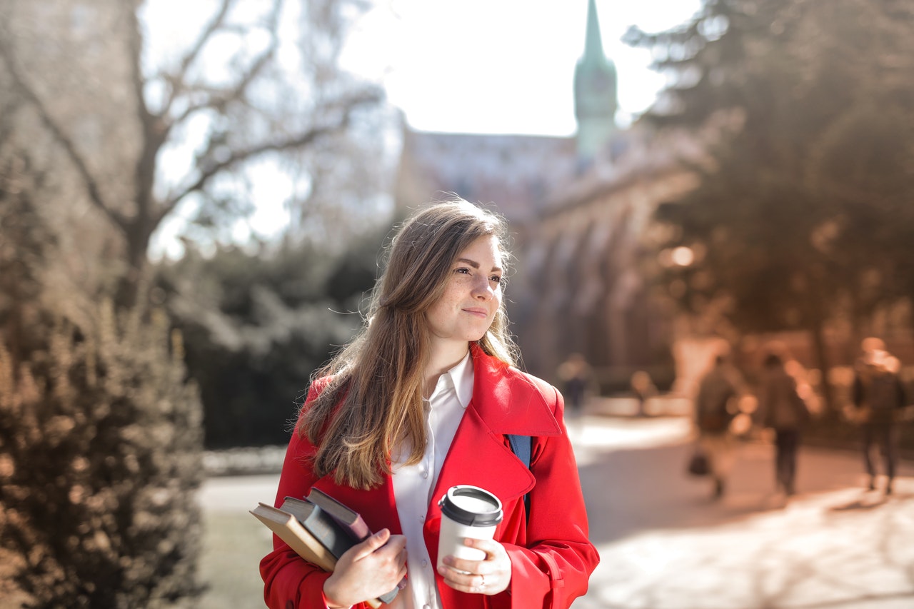 young college student holding books and coffee cup