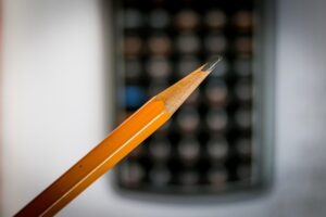 Close up of a pencil infront of a computer screen. The screen is out of focus.